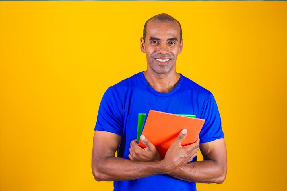 homem em pé segurando material de estudo