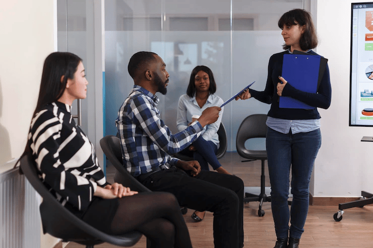 três pessoas sentadas e uma em pé, aprentemente em um processo seletivo
